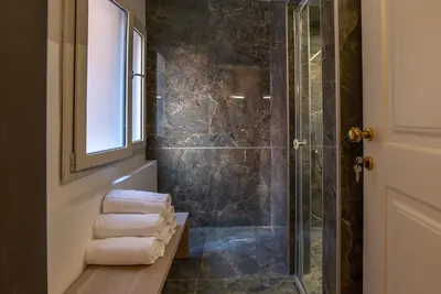 a bathroom with a shower and some towels on a bench at Ora Acanfora Suites in Rome