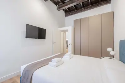 a bedroom with a white bed with a tv on the wall at Rufina's Home in Rome