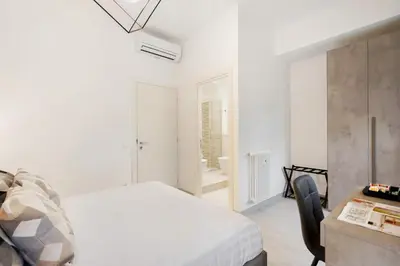 a white bedroom with a bed and a desk at Clodio Welcome - 5 camere arredate con bagno interno - zona comune - condizionatori - in Rome