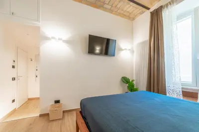 a bedroom with a blue bed and a tv on the wall at Luxury Vatican Rooms - next to the Vatican Museum in Rome