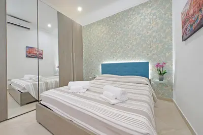 a bedroom with a bed with a blue headboard and flowers at Alba Home Re Di Roma in Rome