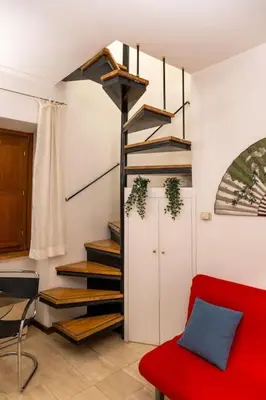 a living room with a red couch and a spiral staircase at Navona Romantic House in Rome