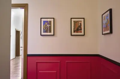 a red wall with three pictures on the wall at TrastevereHome - Elegant Home Near Navona Square in Rome