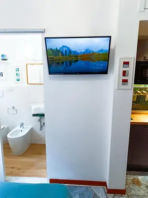 a bathroom with a flat screen tv on a wall at Betania Loft in Rome