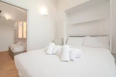 a white bedroom with a large white bed with white pillows at Cozy Rhome in Rome