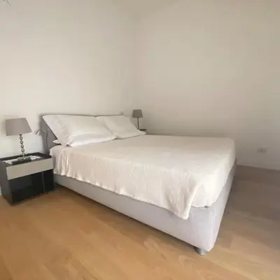 a bedroom with a white bed with a night stand at Appartamento Villa Ada in Rome