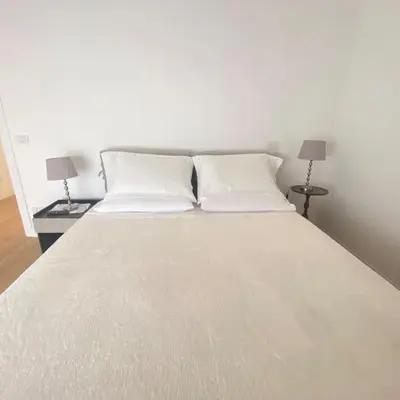 a large white bed with two pillows and two lamps at Appartamento Villa Ada in Rome