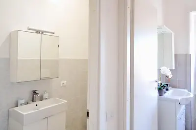 a white bathroom with a sink and a mirror at Casa Cornelia Station in Rome