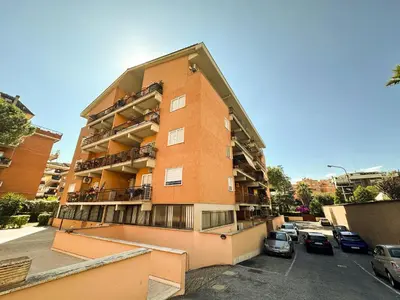 a tall brick building with cars parked in a parking lot at Luminous 2BR Family Apartment in Residential Area in Rome