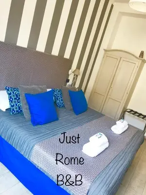 a bed with blue pillows and a sign that says justrano bed at B&B Exa Rooms - Just Rome in Rome