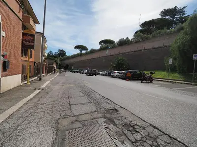 an empty street with cars parked on the side of a wall at Giulia's Vatican Apartment Saint Peter in Rome