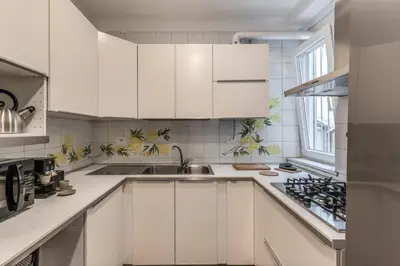 a white kitchen with white cabinets and a sink at Frattina Grand Suite - Vacanze Romane Apartments in Rome