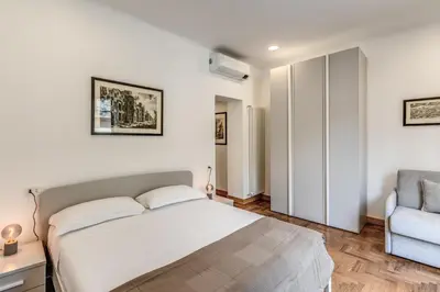 a white bedroom with a bed and a chair at Frattina Grand Suite - Vacanze Romane Apartments in Rome