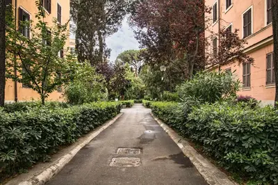 an empty street between two buildings with bushes at Esa apartment Flaminio in Rome