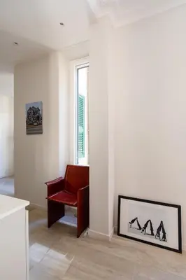 a living room with a red chair and a window at Suite Lucrezio in Rome in Rome