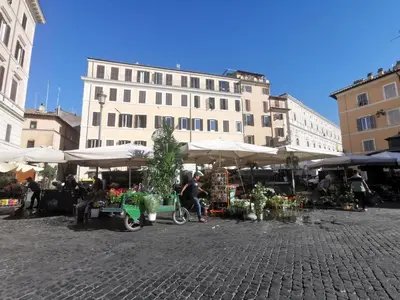 a market with tables and umbrellas in front of a building at 