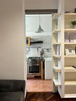 a room with a kitchen with a stove and a room with a couch at Suite Vaticana 9 in Rome