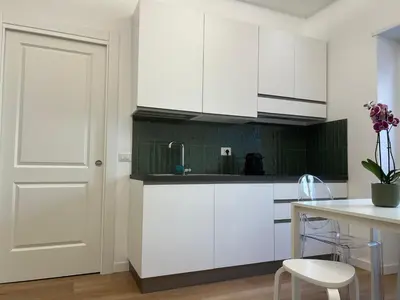 a kitchen with white cabinets and a table and a door at Simon's House in Rome