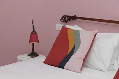 a bed with white sheets and pillows and a lamp at YCH-Vintage flat near San Giovanni in Rome