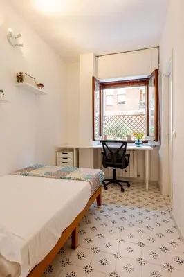 a bedroom with a bed and a desk and a window at Modern apartment in Portuense in Rome