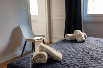 two towels on a bed with a chair and a window at Barigelli Apartment in Rome