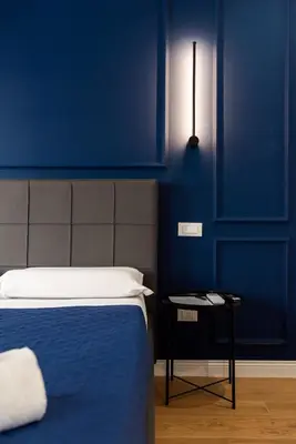 a bedroom with blue walls and a bed with a side table at Barigelli Apartment in Rome