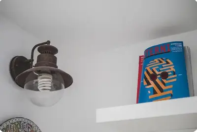a light on a white shelf with a book at Green House in Rome
