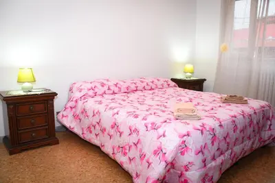 a bedroom with a pink bed and a wooden night stand at A Casa di Lilly in Rome
