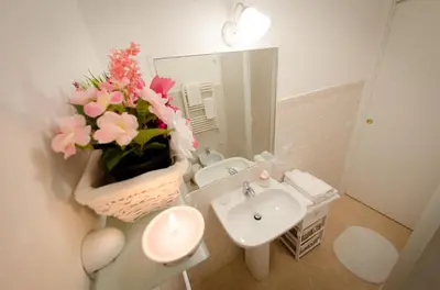 a bathroom with a sink and a vase of flowers at Romance al Colosseo in Rome