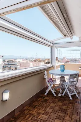 a balcony with a table and chairs and a large window at Cozy Penthouse with Terrace and Rome View in Rome
