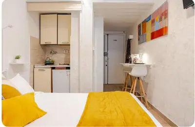 a bedroom with a white bed and a kitchen at Minisuite a Borgo Pio 