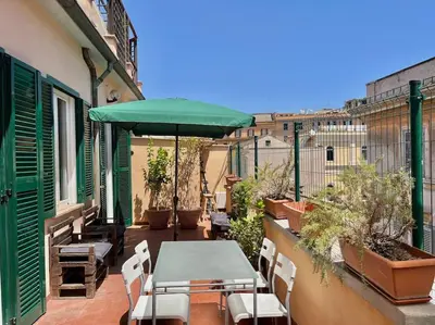 a patio with a table and umbrella on a balcony at Roma San Pietro rooftop view in Rome