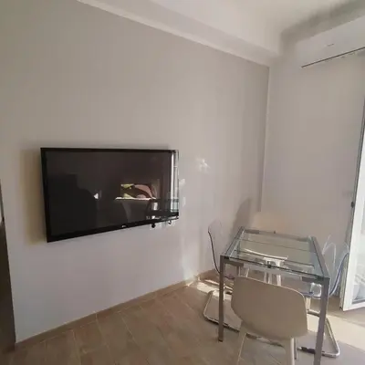 a living room with a glass table and a tv on the wall at Caravaggio Inn in Rome