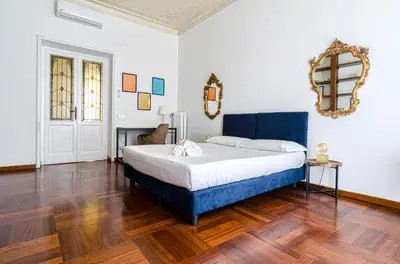 a bedroom with a blue bed and a mirror at AMOE - Eleganza e Storia nel Cuore di Roma in Rome