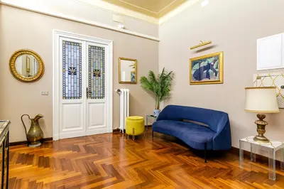 a living room with a blue chair and wooden floors at AMOE - Eleganza e Storia nel Cuore di Roma in Rome