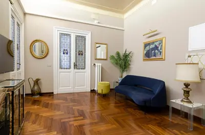 a living room with a blue chair and wooden floors at AMOE - Eleganza e Storia nel Cuore di Roma in Rome