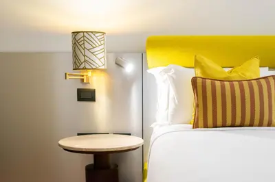 a bed with a yellow headboard next to a table at The Couper Umiltà in Rome