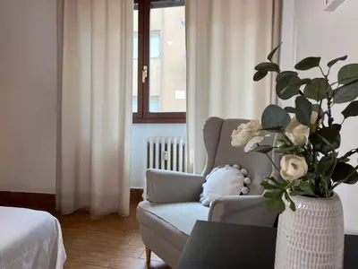 a living room with a chair and a vase with flowers at Fall in love with Roma Vaticano - 5 Minutes from the Vatican - balcony with a view in Rome
