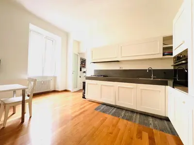 a kitchen with white cabinets and a wooden floor at Anna Rome Vatican Luxury in Rome