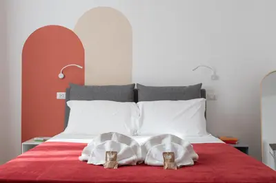 a bed with two white pillows on a red blanket at Alba Terrace - Rome Modern Apt Close to Metro in Rome