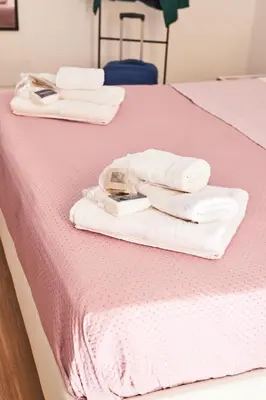 two white towels are sitting on a pink bed at Napodano Apartments - Roma in Rome