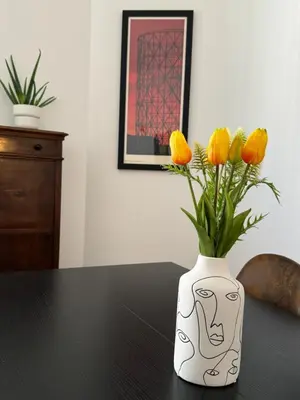 a white vase with yellow flowers in it on a table at Casa Palmiero in Rome