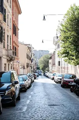 a street with cars parked on the sides of the road at Lion Renting Colosseum in Rome
