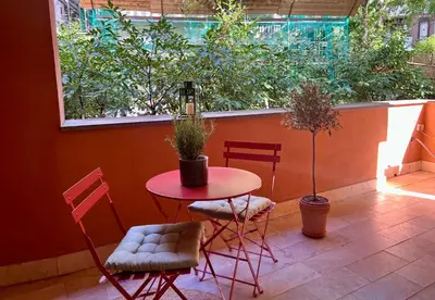 a red table and chairs in a patio with trees at Elegant Apartment Vallombrosa 55 in Rome