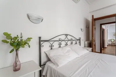 a bedroom with a white bed with a vase of flowers at iFlat Vatican Spacious Apartment with Terrace in Rome