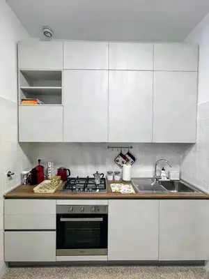 a kitchen with white cabinets and a stove and a sink at Casa vacanza Brandi in Rome