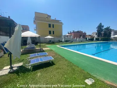a pool with lounge chairs and an umbrella next to a building at Casa e Appartamento per Vacanze JASMINE in Rome