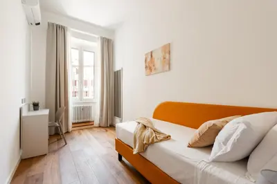 a bedroom with a bed with white walls and wooden floors at Elegant Haven Re di Roma by Hostand in Rome