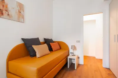 a orange couch in a living room with a table at Elegant Haven Re di Roma by Hostand in Rome