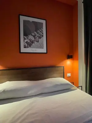 a bedroom with a white bed with an orange wall at Maison Adelaide in Rome